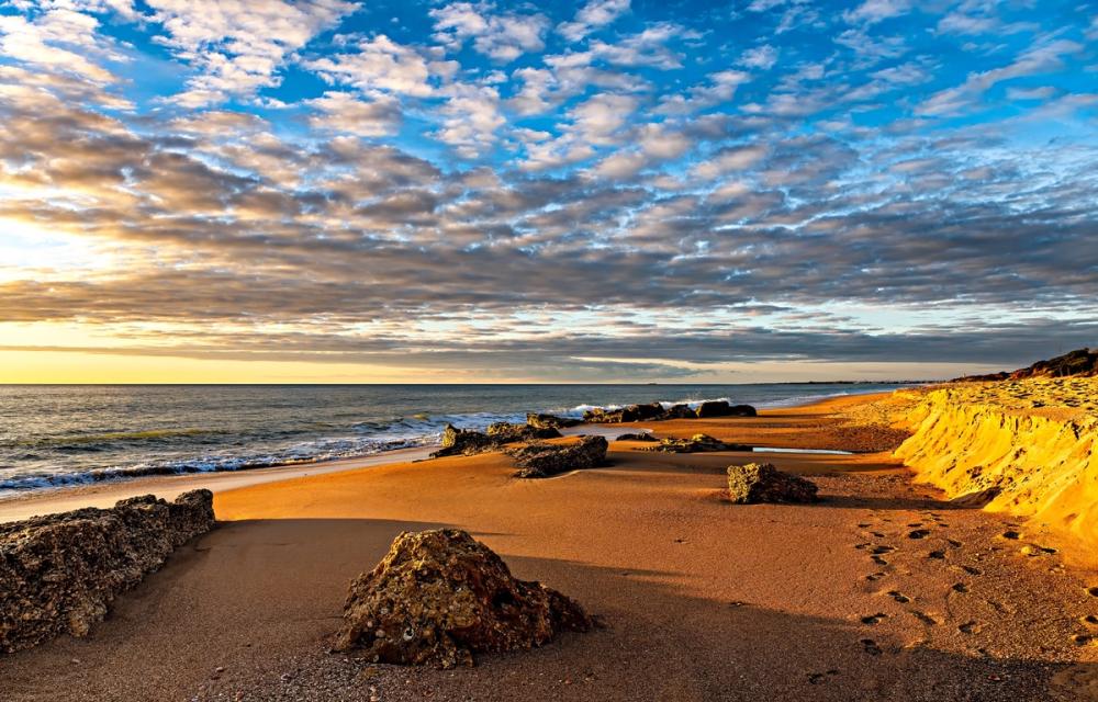 Solnedgang lager varme farger over stranden ved Conil de la Frontera