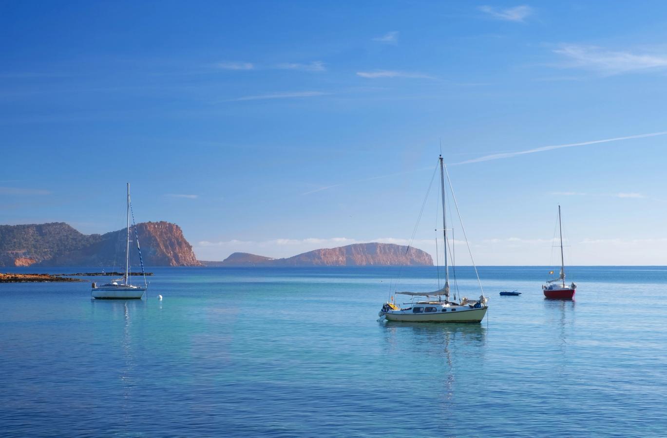 Bildet viser det turkisblå havet med båter og fjell i bakgrunnen. 