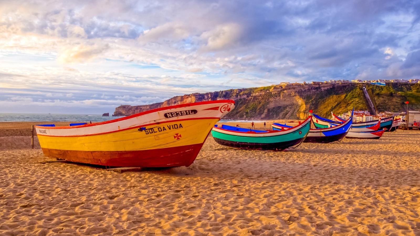 Tradisjonelle, fargerike fiskebåter på stranden i Nazare