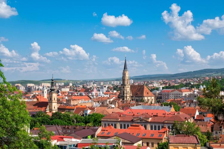 Utsikt over sentrum av Cluj Napoca i Romania med røde tak blant grønn natur