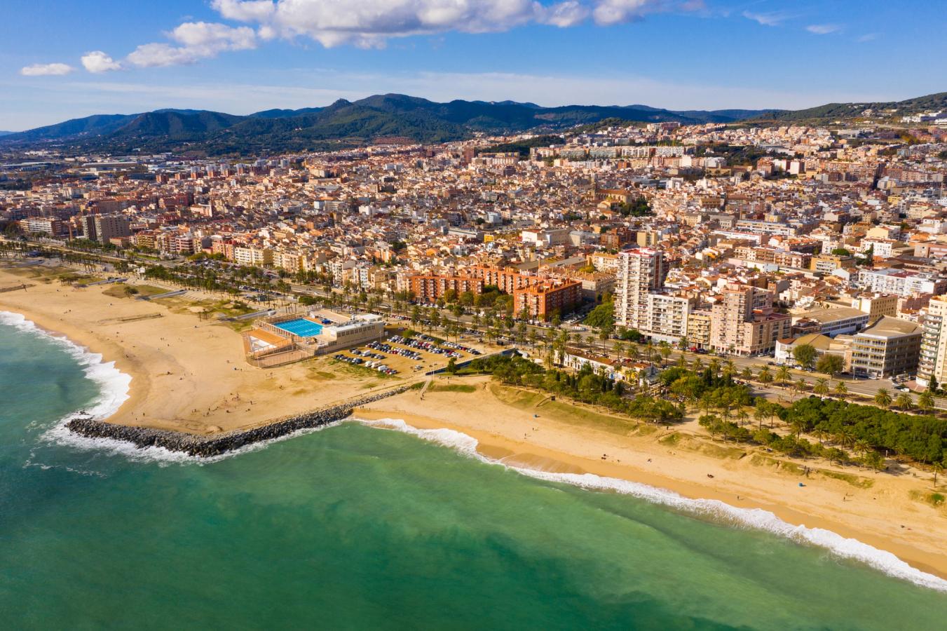 Luftfoto av Mataró, en kystby nord for Barcelona, med brede sandstrender, strandpromenade, bygninger og Middelhavet i forgrunnen