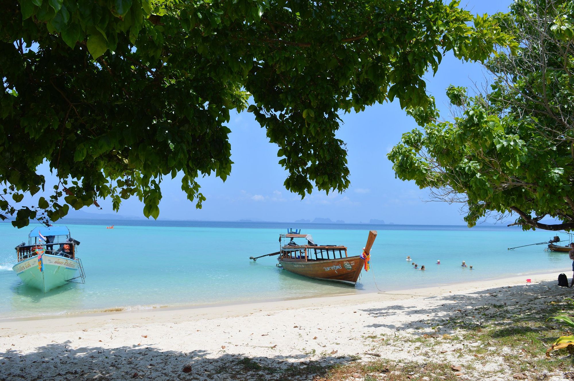 Hvit sandstrand med turkis hav og lokale båter på Kata Beach i Phuket, Thailand
