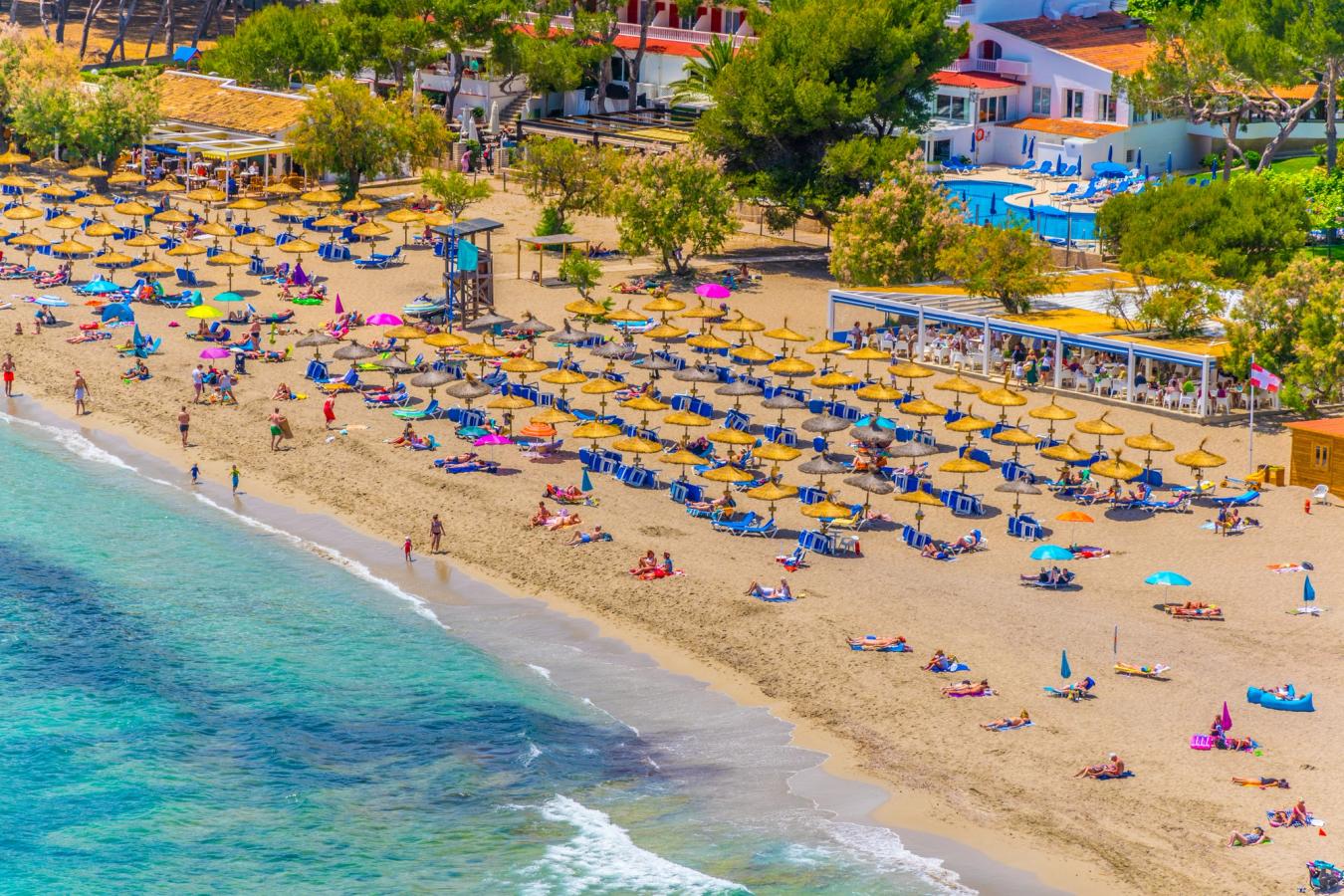 Bilden visar stranden i Canyamel med solstolar och parasoller och det blå, klara havet