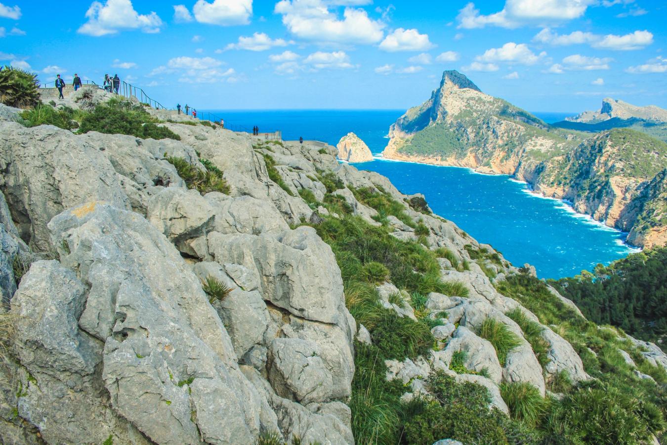 Bildety viser Cap de Formentor, kun 30 minutter med bil nord for Alcudia. Fjellformasjoner rundt en bukt ut mot sjøen. Bratte klippevegger.