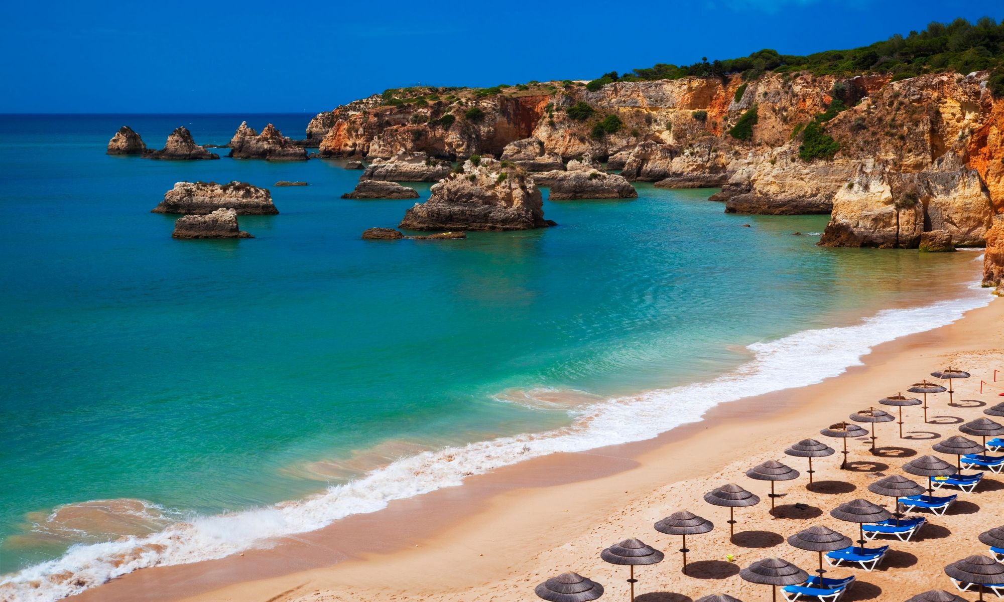 Utsikt over det krystallklare havet, stranden og klippene langs Algarvekysten i Portugal