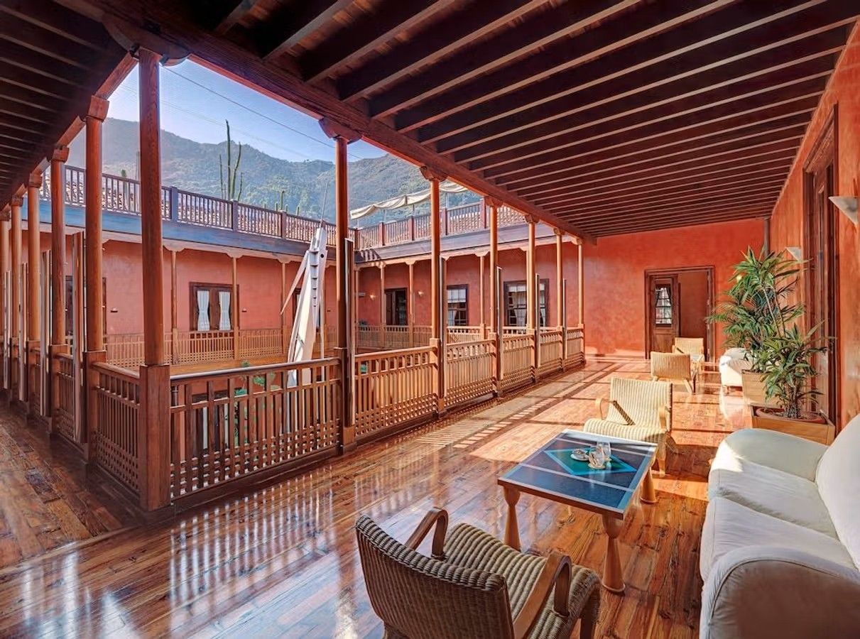Et atrium på Hotel San Roque i Garachico på Tenerife. Vægge i en rødbrun farve, mens gulv og bærende konstruktioner i øvrigt er i træ.