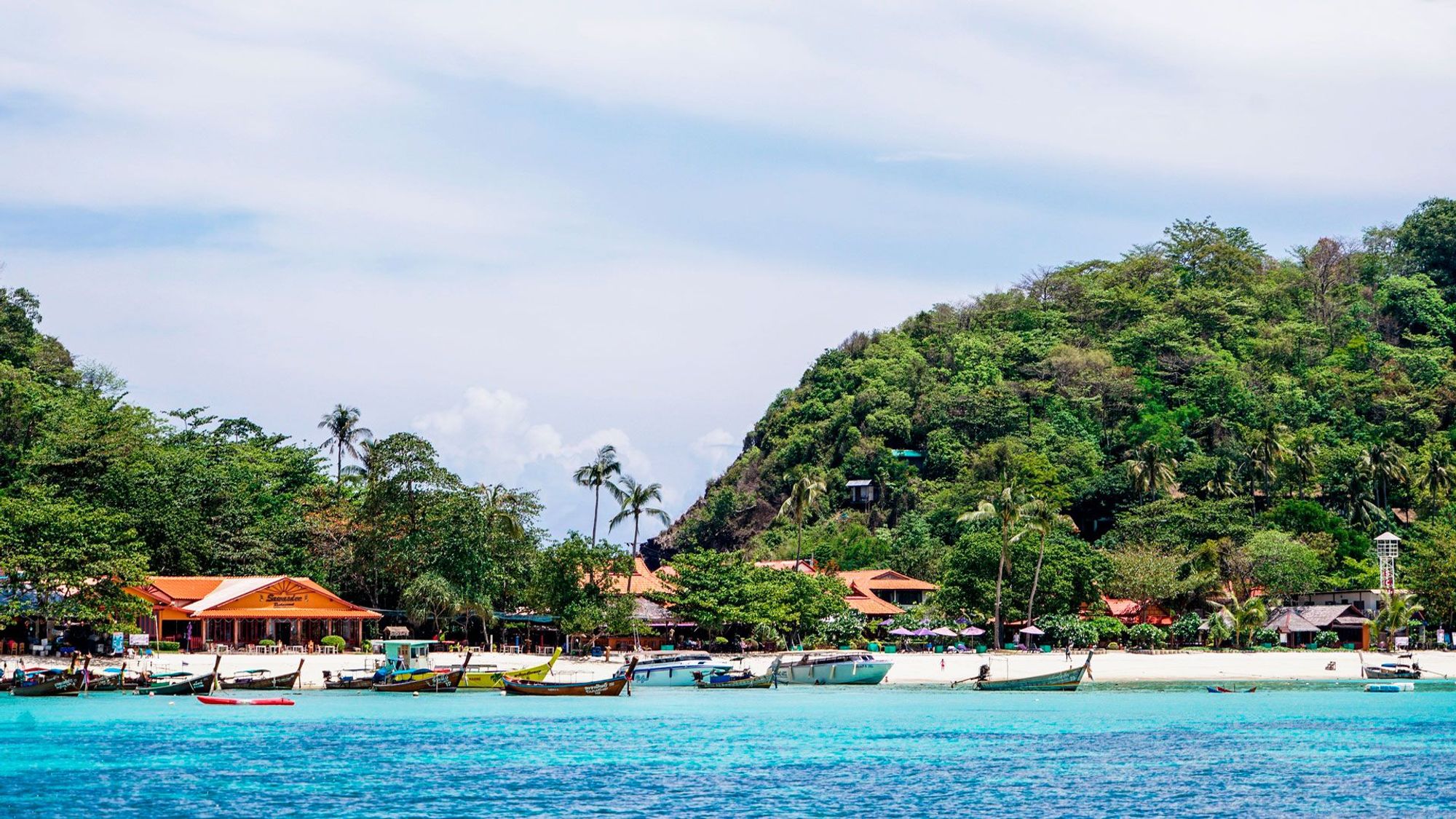 Hvid sandstrand og azurblåt hav omgivet af frodig natur i Kamala på Phuket i Thailand.