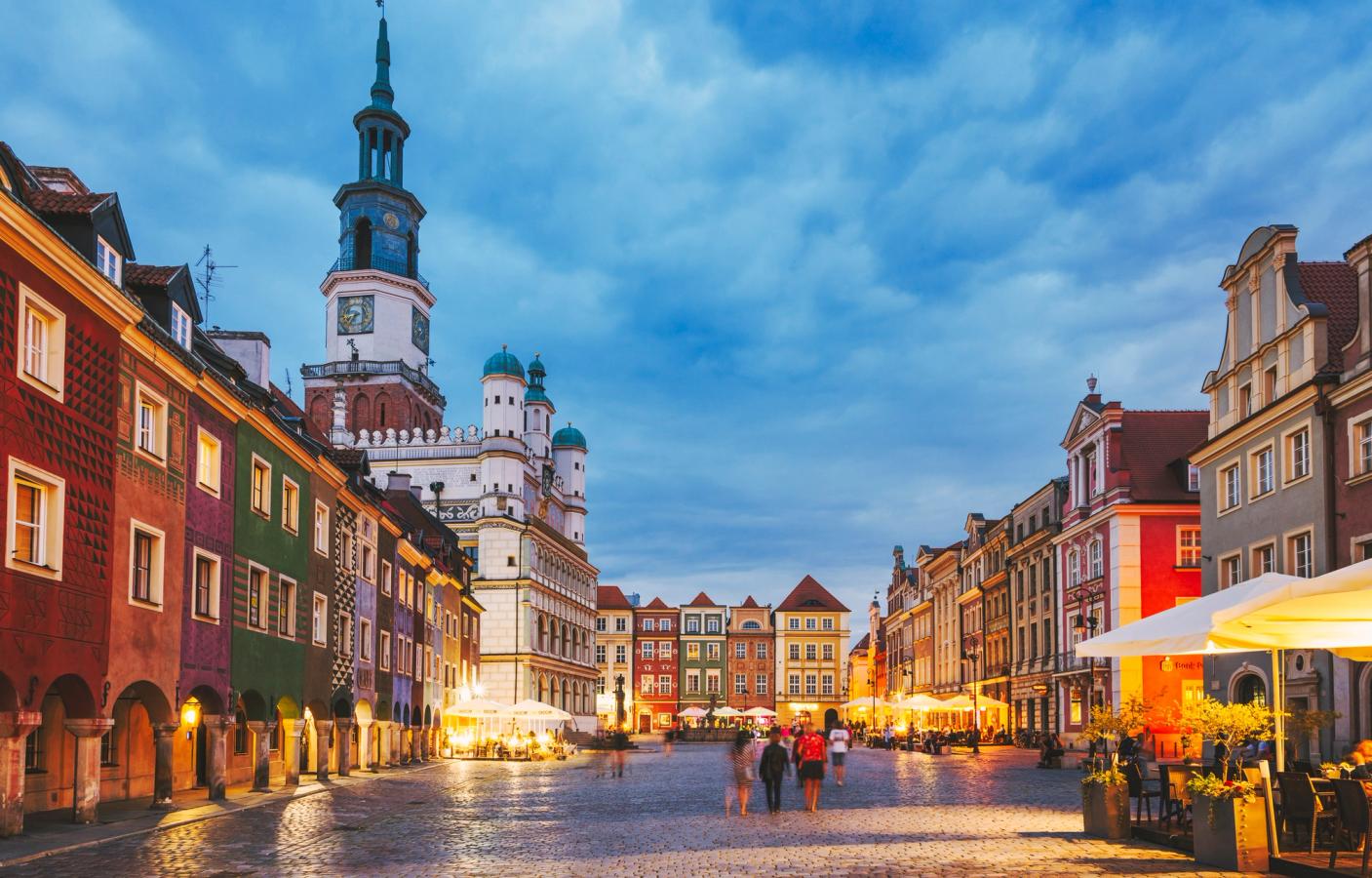 Bildet viser plassen Stare Miasto i gamlebyen i Poznan. Plassen er brosteinsbelagt med eldre arkitektur, med fargerike bygninger, på begge sider. Det er kveld og enkelte mennesker spaserer på plassen.