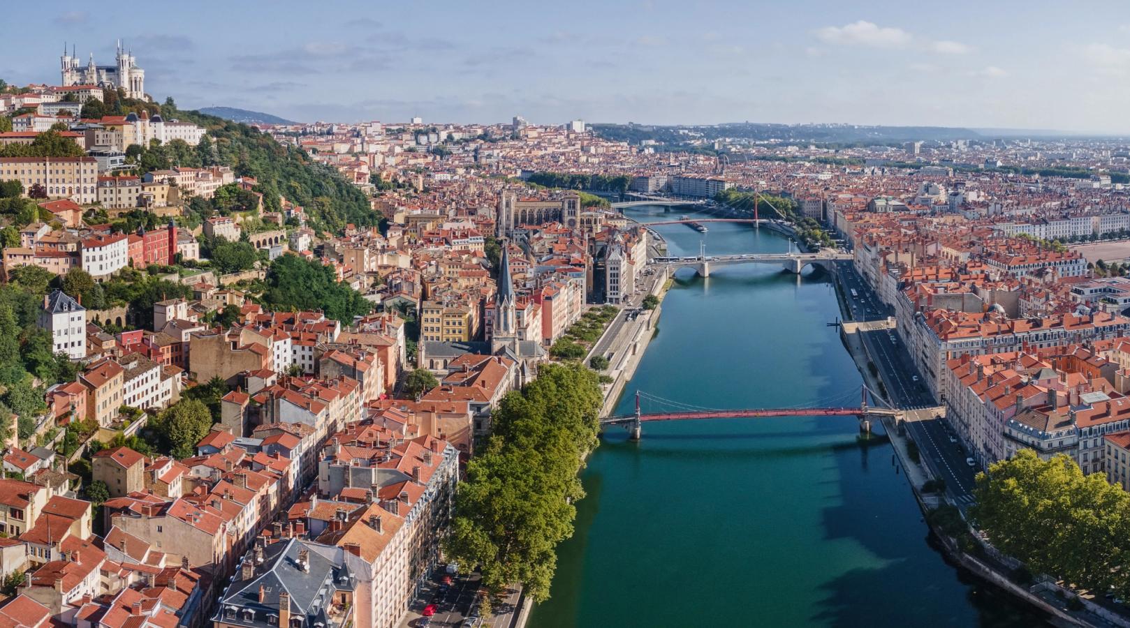 Lyon med sine mange huse med røde tegltage, grønne træer og Rhône-floden, der løber tværs gennem byen. 