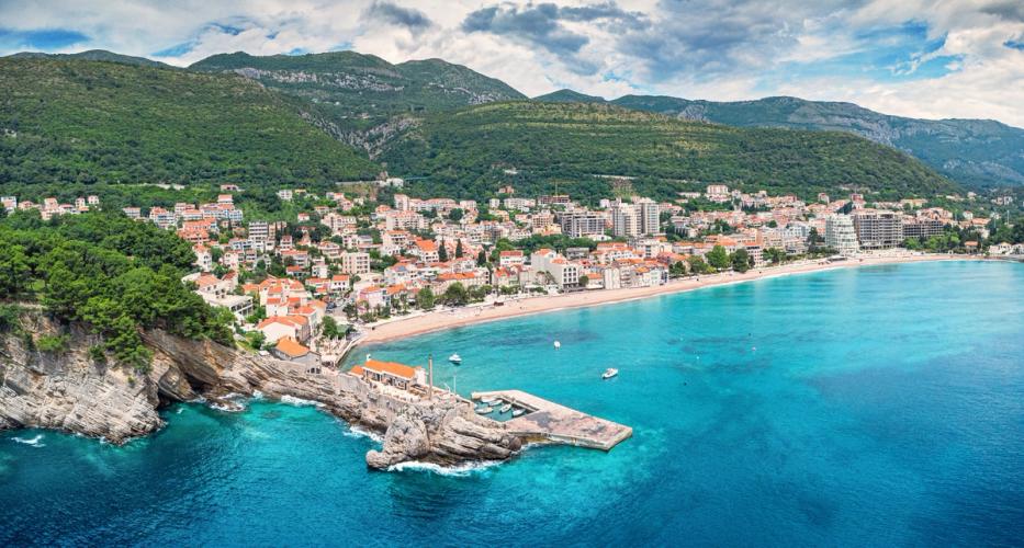 Utsikt over byen, stranden og det azurblå havet i Petrovac i Montenegro