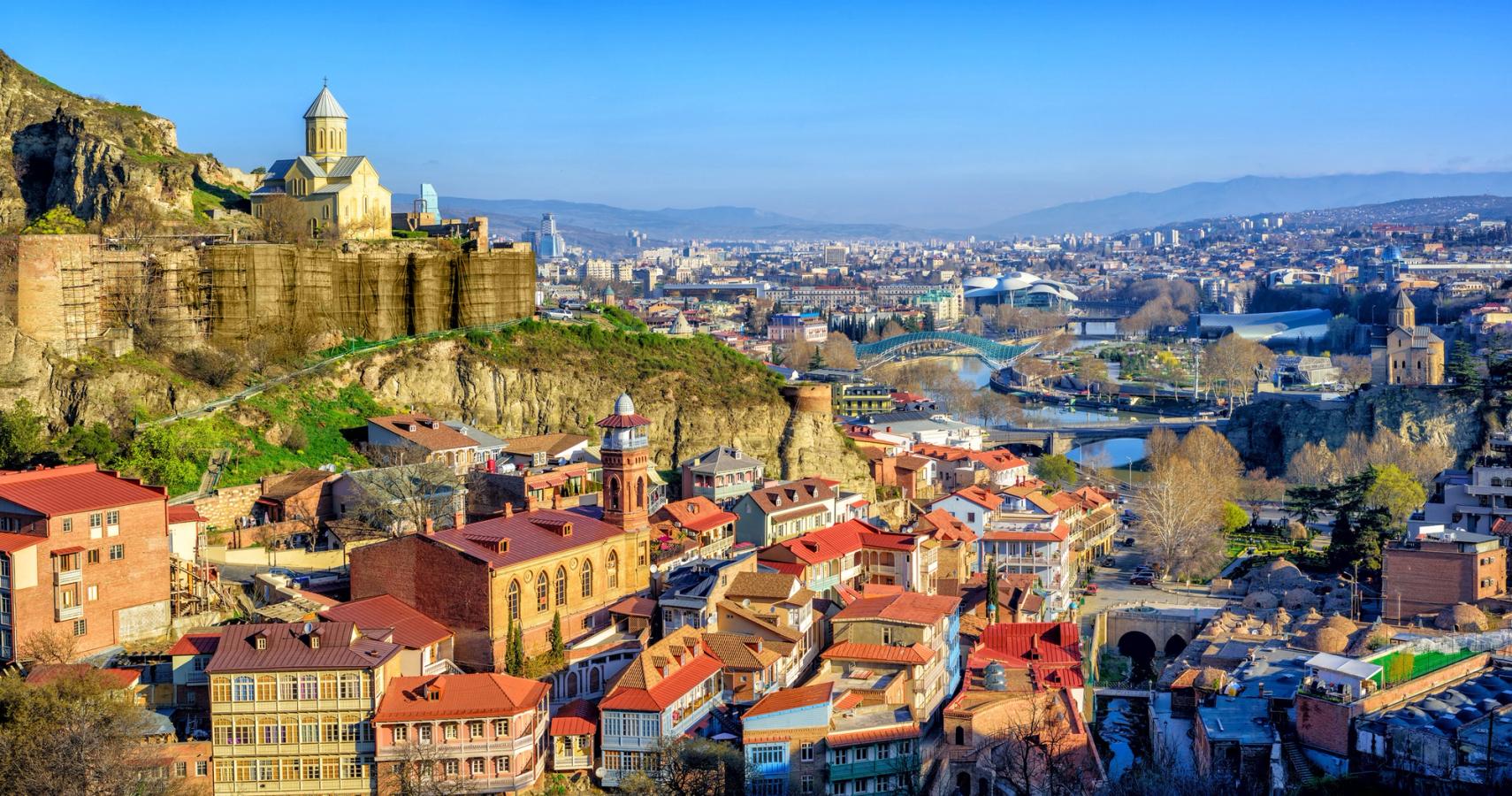 Georgiens hovedstad Tbilisi badet i sollys under en klar blå himmel.