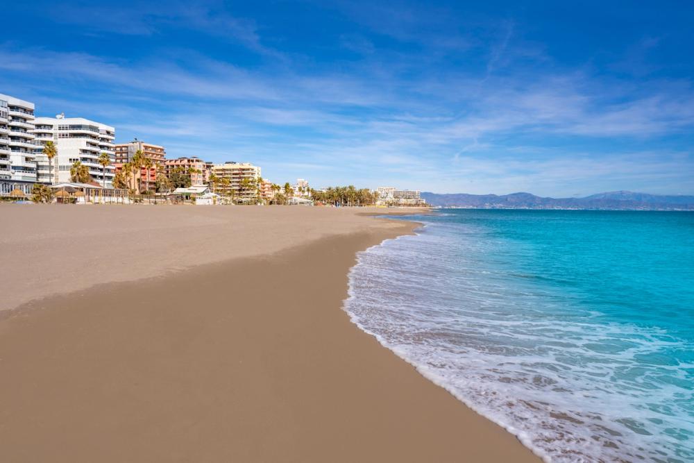 Langgrunn og finkornet sandstrand i Torremolinos med bebyggelse til venstre