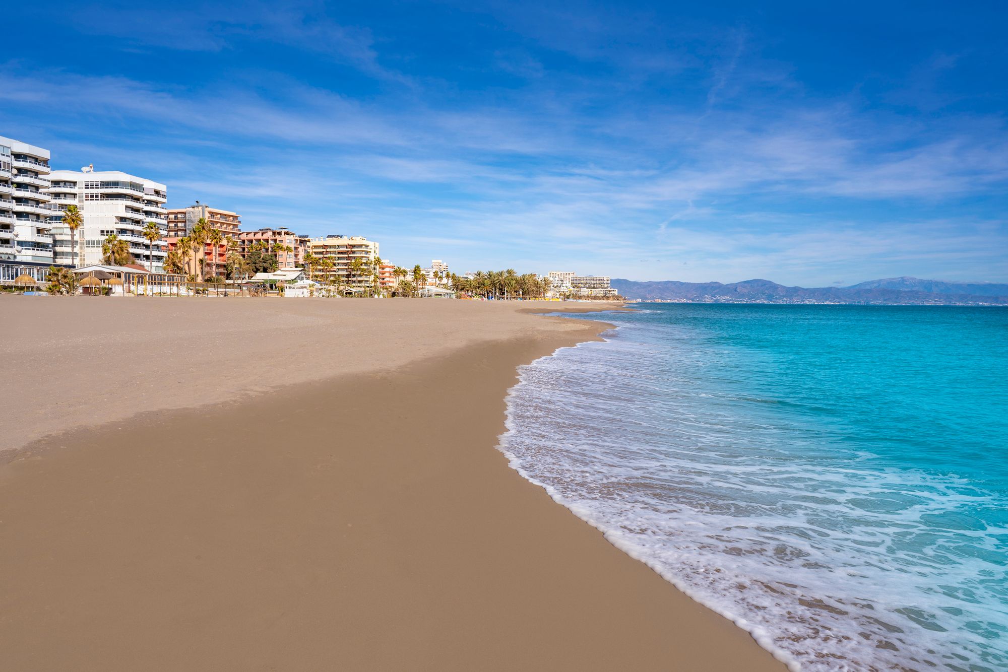 Langgrunn og finkornet sandstrand i Torremolinos med bebyggelse til venstre
