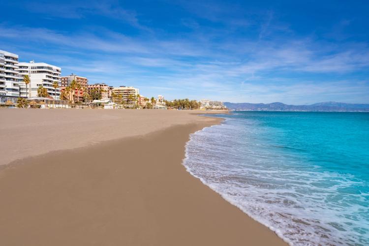 Lavvandet og finkornet sandstrand i Torremolinos med bebyggelse til venstre.