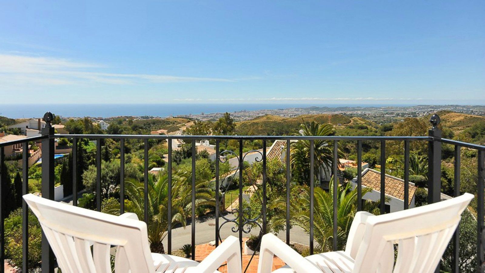 To hvide lænestole står vendt ud mod landskabet og havet