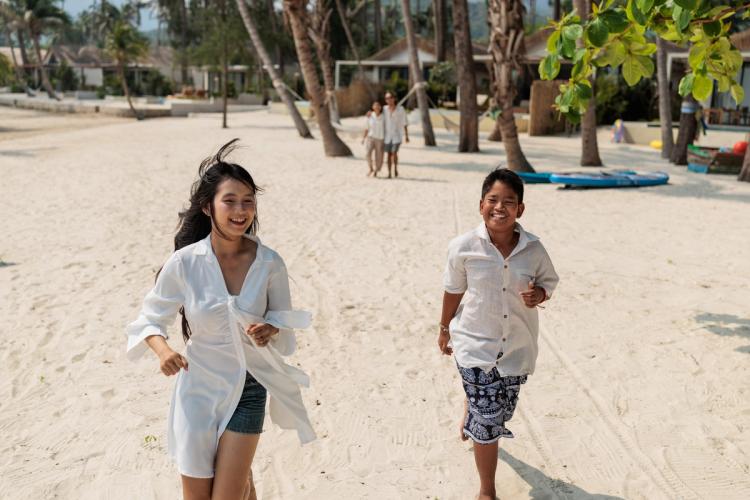 Glade børn som løber på en dejlig hvid sandstrand i Thailand