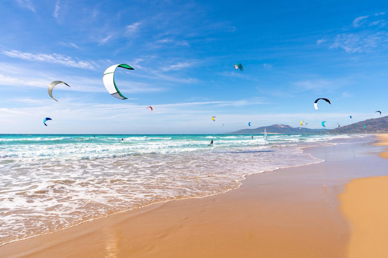 Bildet viser stranden ved Tarifa med mange kitesurfere. 