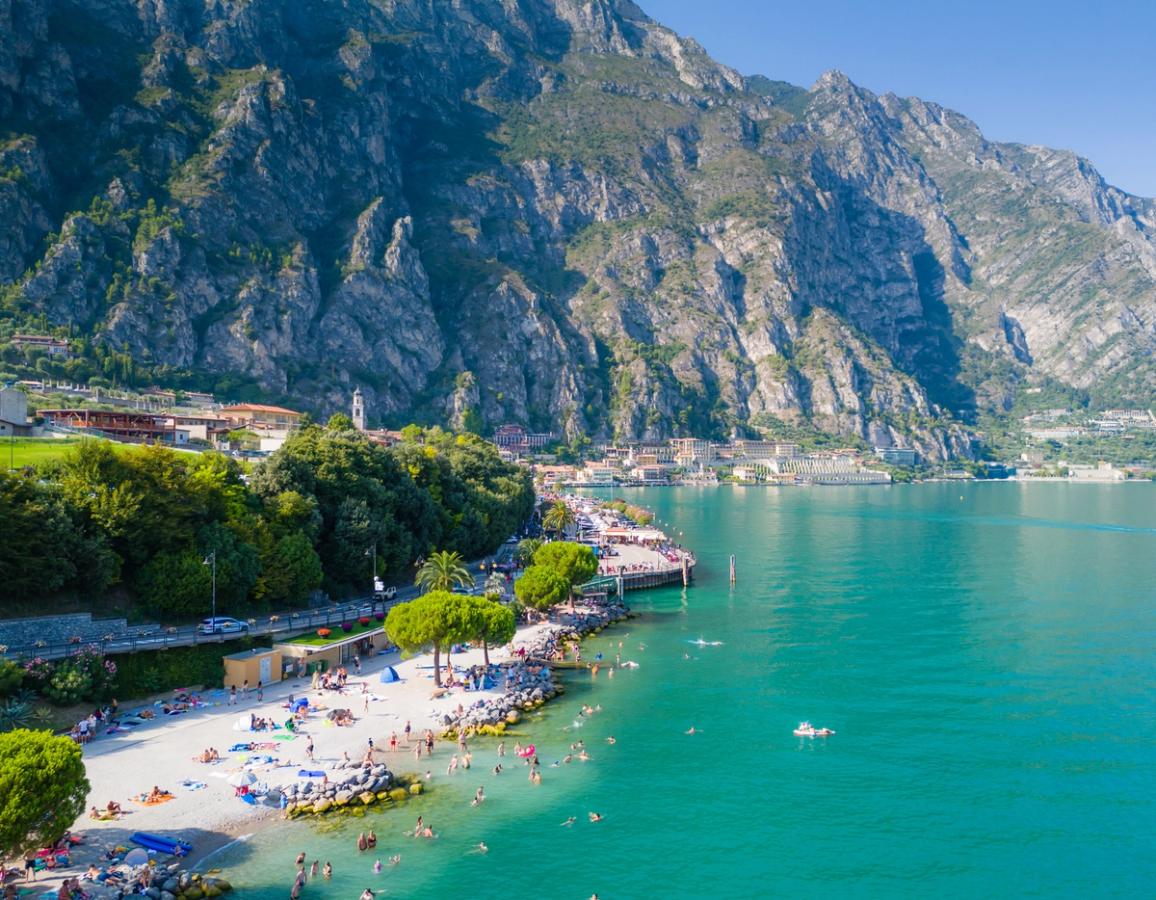 Utsikt til stranden og Gardasjøen i Limone sul Garda omkranset av steile fjell