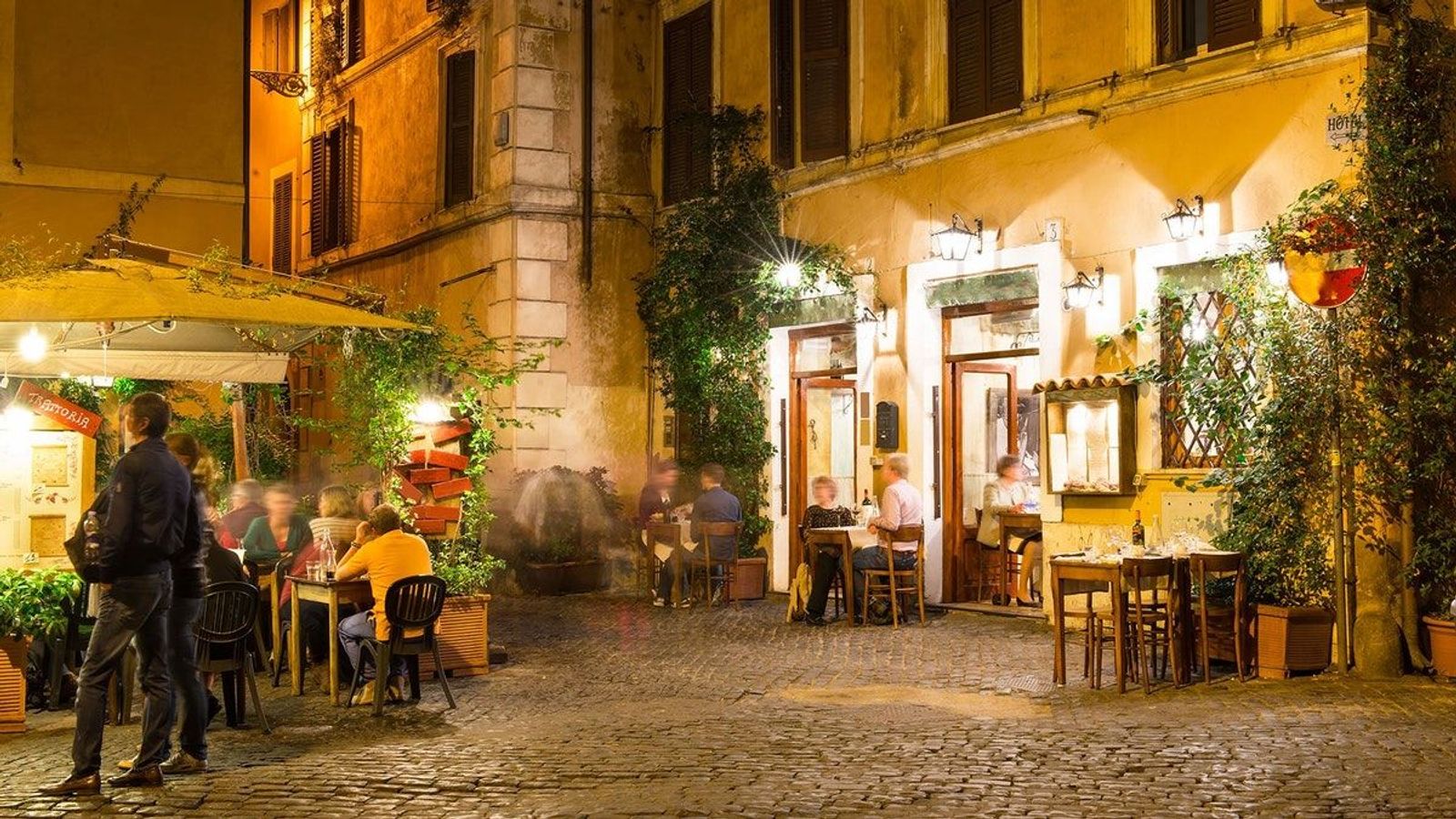 Bildet viser et mindre torg i Trastevere i Roma hvor gjester utendørs nyter vin, mat, samtalen og den store kjærligheten