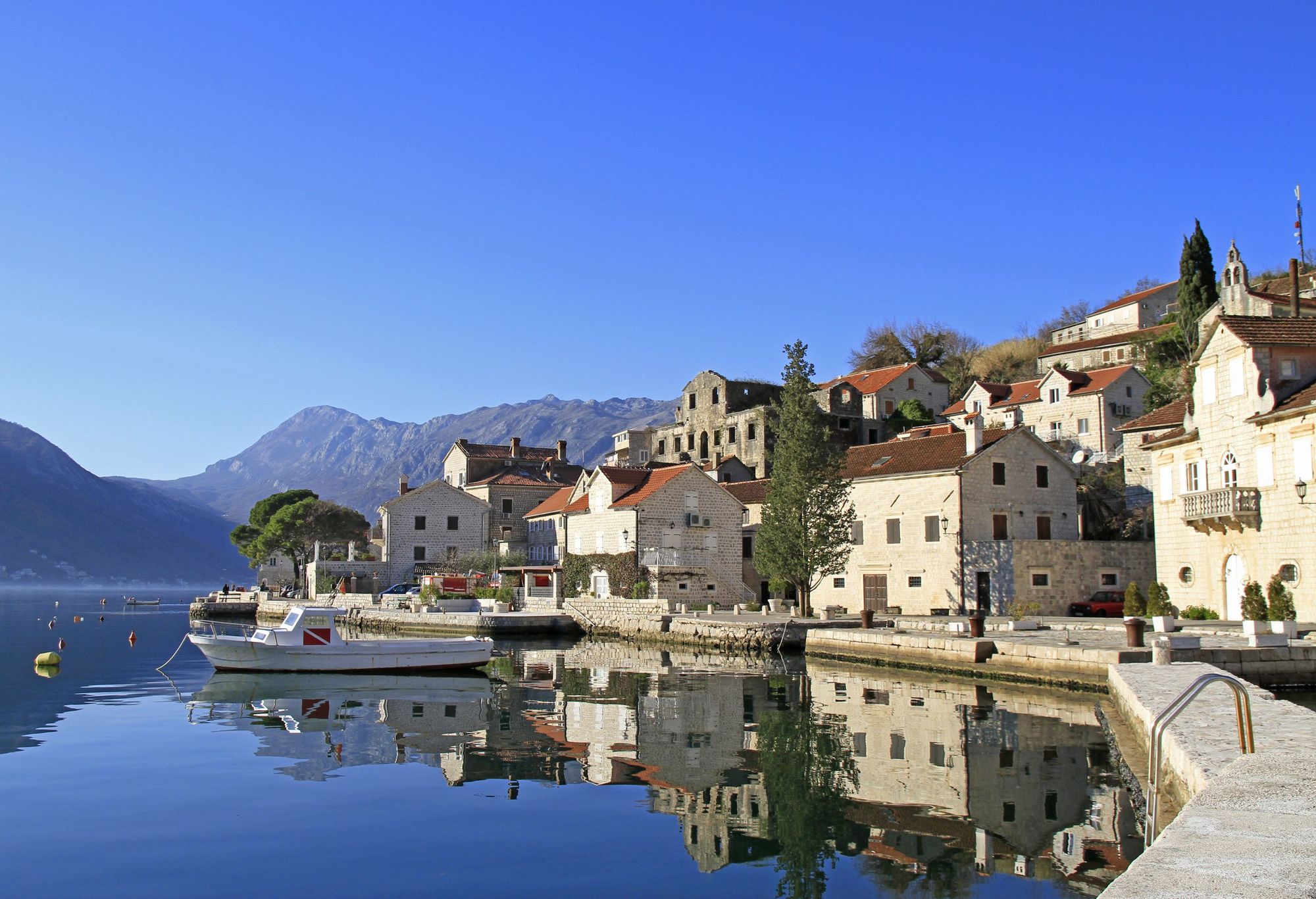 Utsikt over havnepromenaden, gamle hus og fjellene i bakgrunnen i Perast ved Kotorbukta i Montenegro