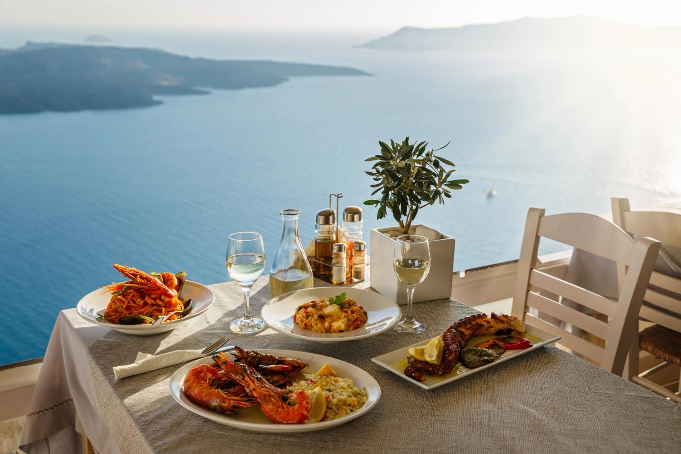 Bordet er dekket til en romantisk middag for to i solnedgangen på Santorini med panoramautsikt over havet