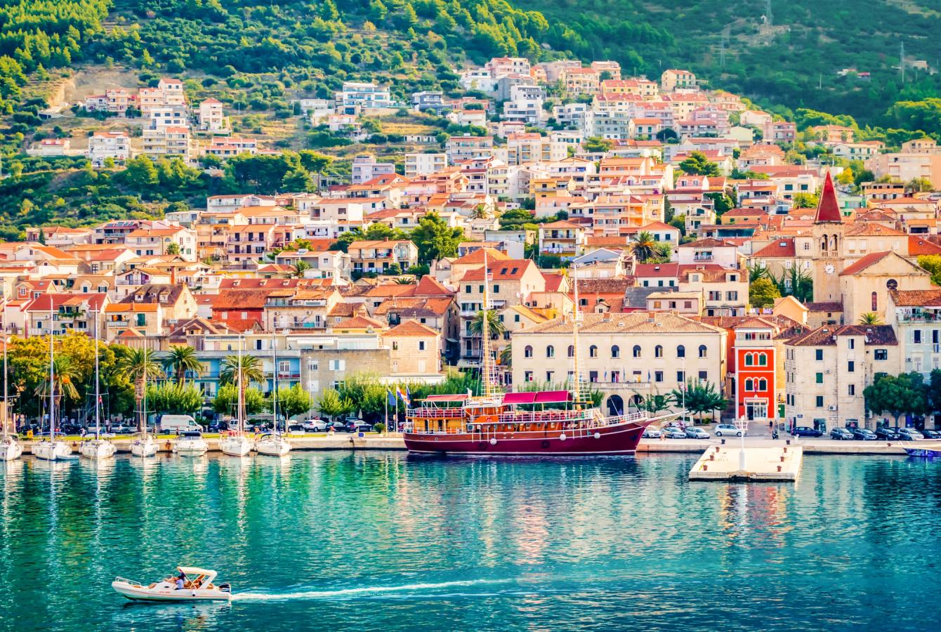 Fargerike hus i åssiden og krystallklart vann i havnen i Makarska by i Kroatia