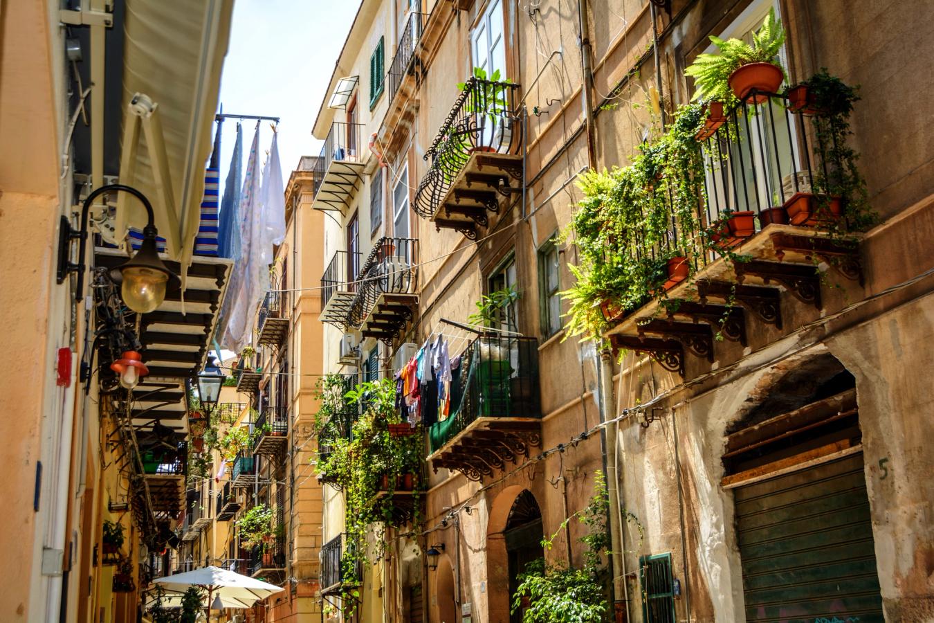 Bildet viser en hyggelig og karakteristisk gate i sentrum av Palermo på Sicilia. Med sine balkonger hvor klesvask og blomsterkasser lever side om side.