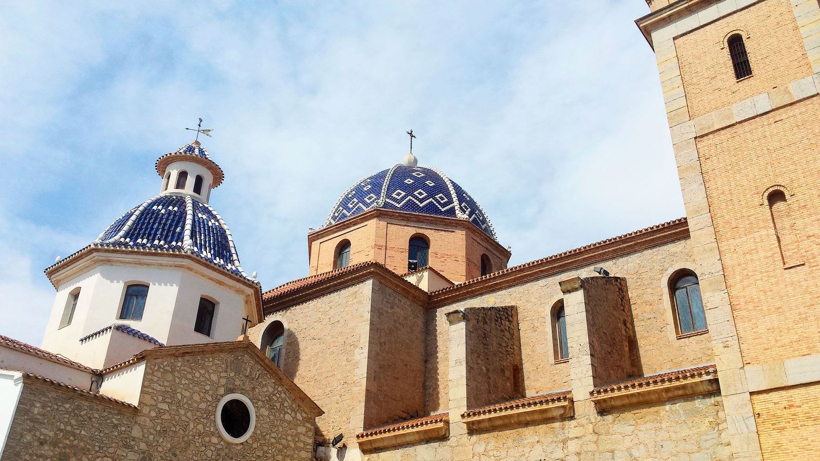 Kirken Nuestra Señora del Consuelo i Altea med blå kupler og fasade i stein og murstein mot en lys himmel