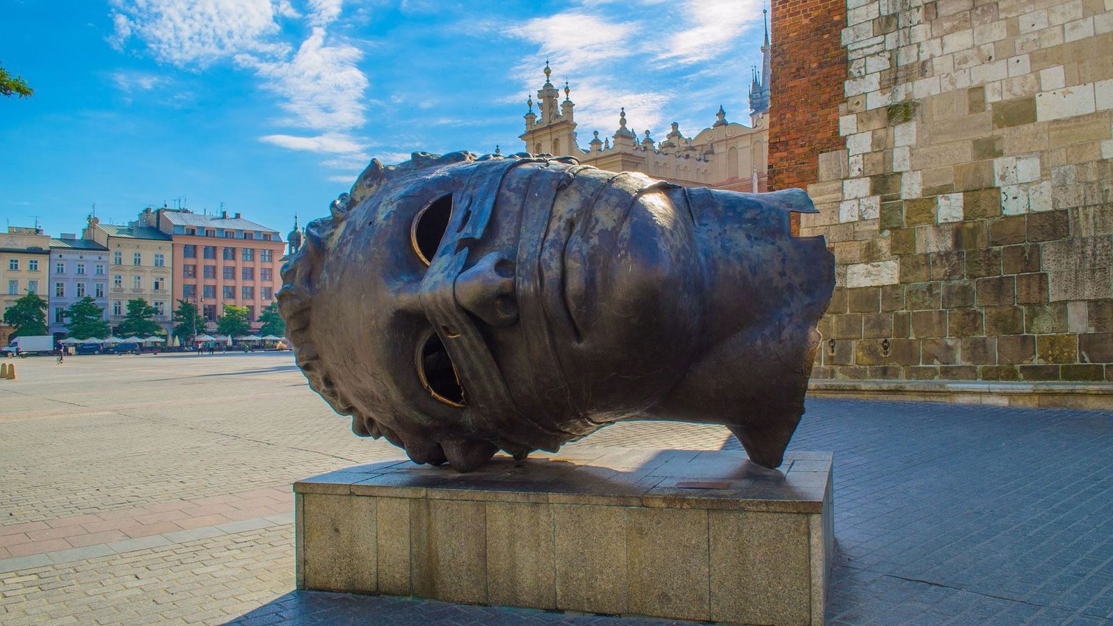 Billedet viser kunstværket Eyeless Head i Krakow. Et liggende hoved i bronze, hvor øjnene mangler. Hovedet er placeret på en sokkel.
