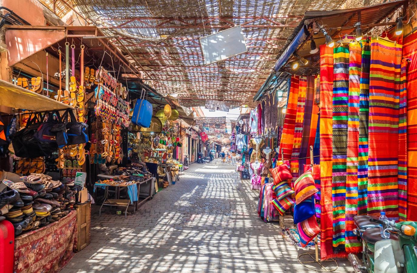Shoppinggata från marknaden Jemaa el-Fna i Marrakech, där färgstarka mattor, kläder och andra souvenirer hänger på var sin sida.