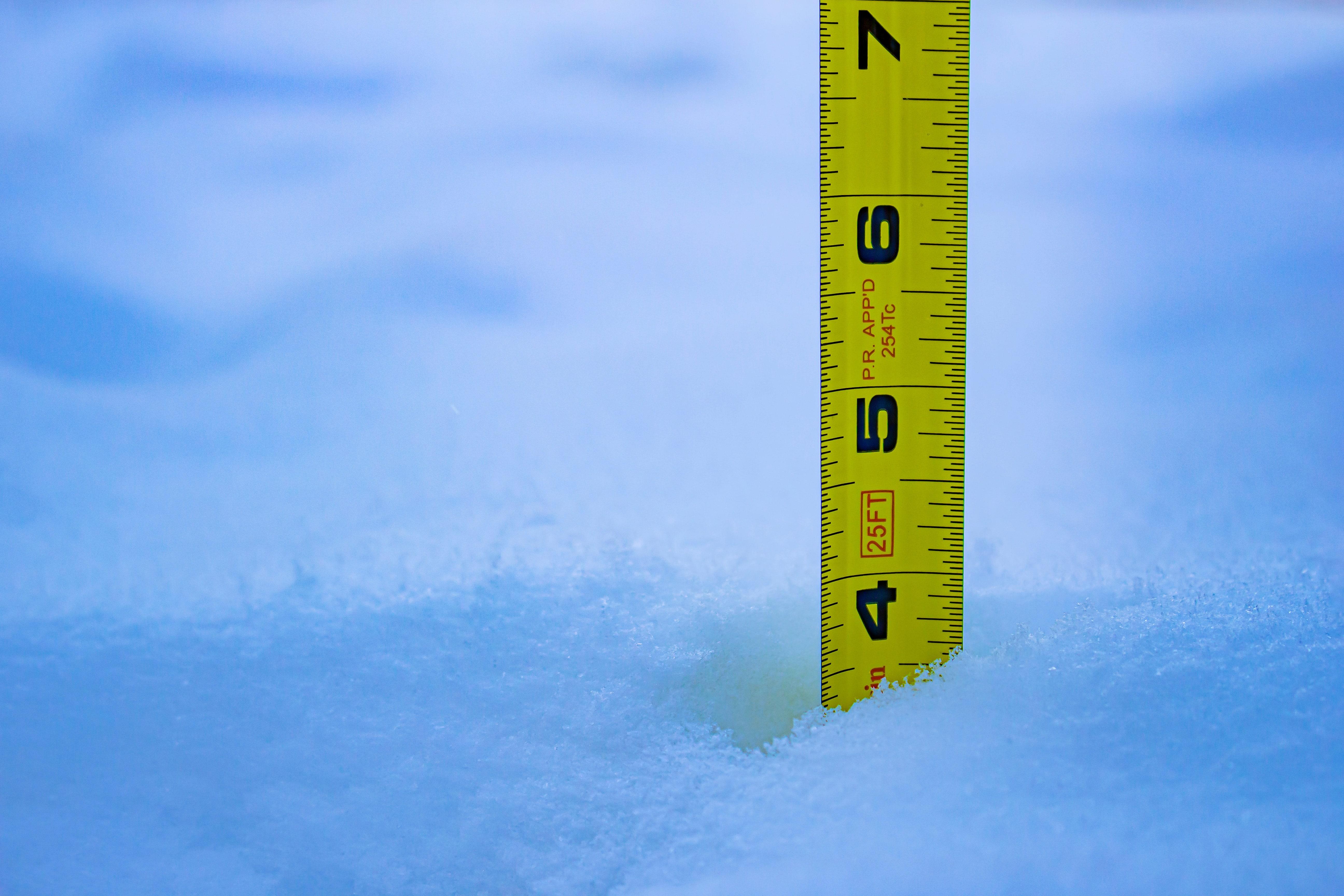 Mètre ruban planté dans la neige fraîche pour mesurer la hauteur d'enneigement