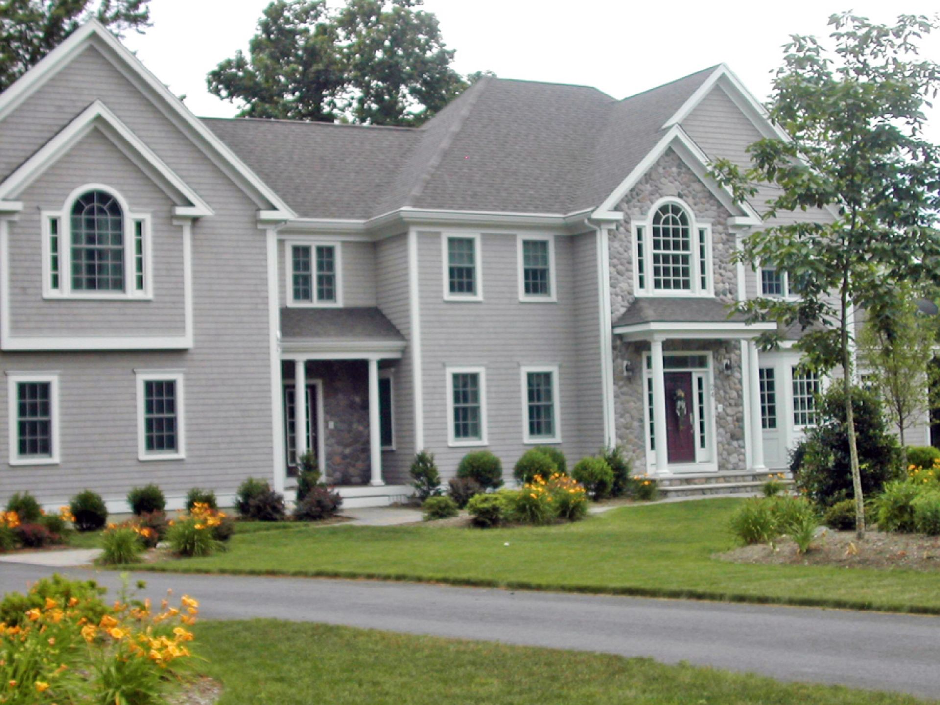 Nelson Painting is a third-generation painting business that provides exterior house painting, shown here after a colonial gray siding stone accents project