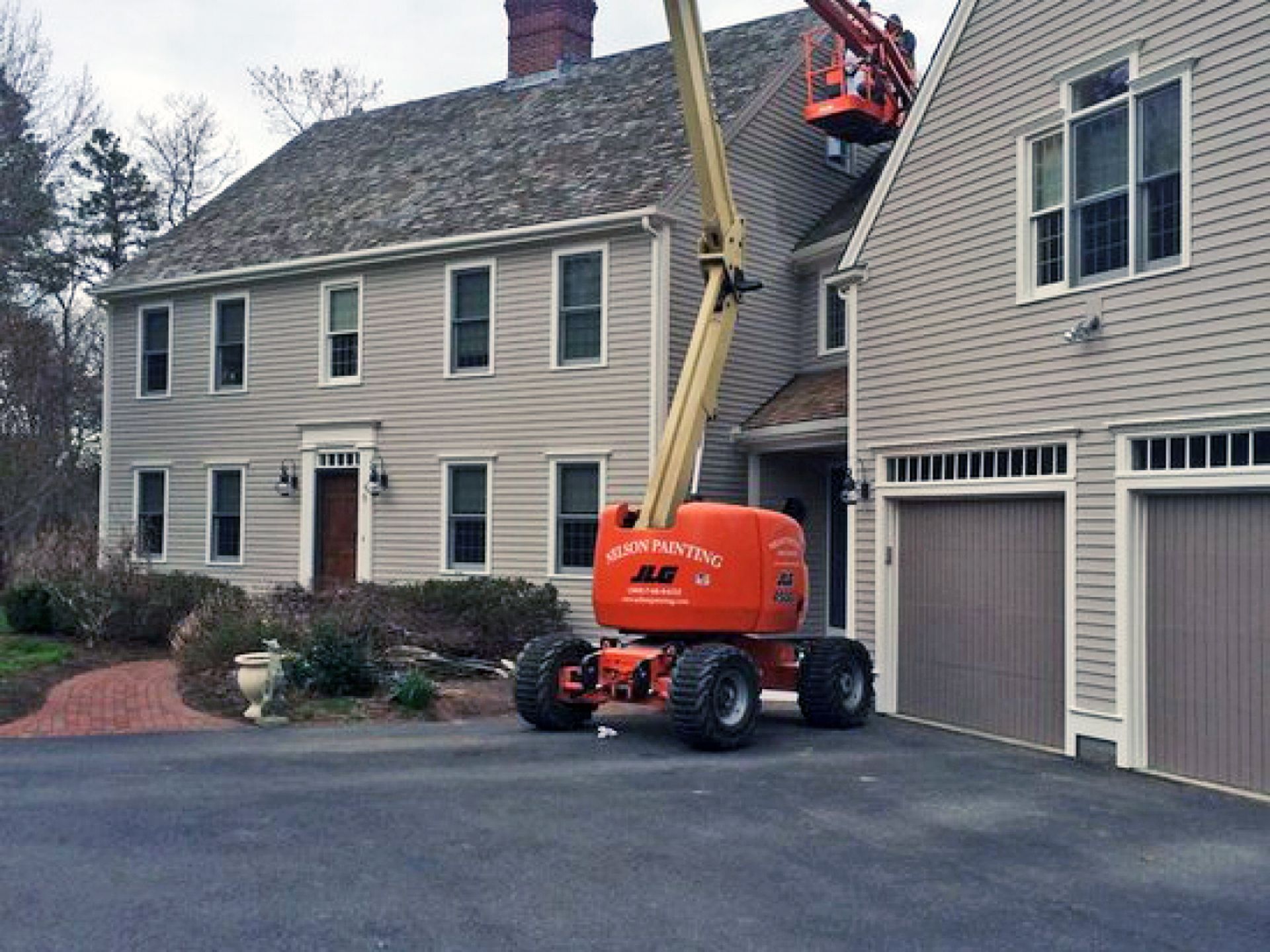 Nelson Painting is a local house-painting business that provides exterior house painting, shown mid-project on a colonial boom lift nelson truck job