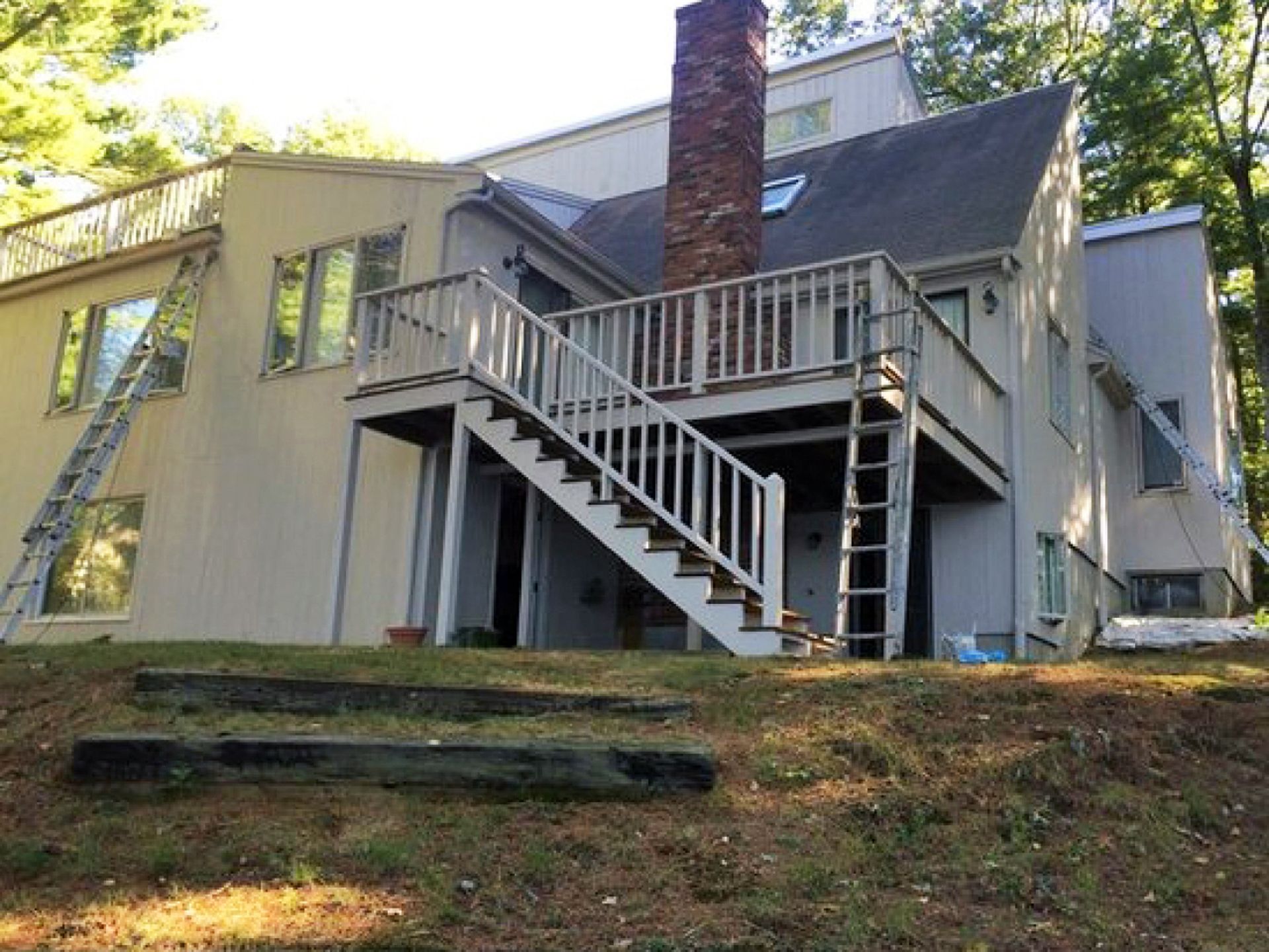 Nelson Painting is a local house-painting business that provides exterior house painting, shown mid-project on a contemporary deck ladders rear job