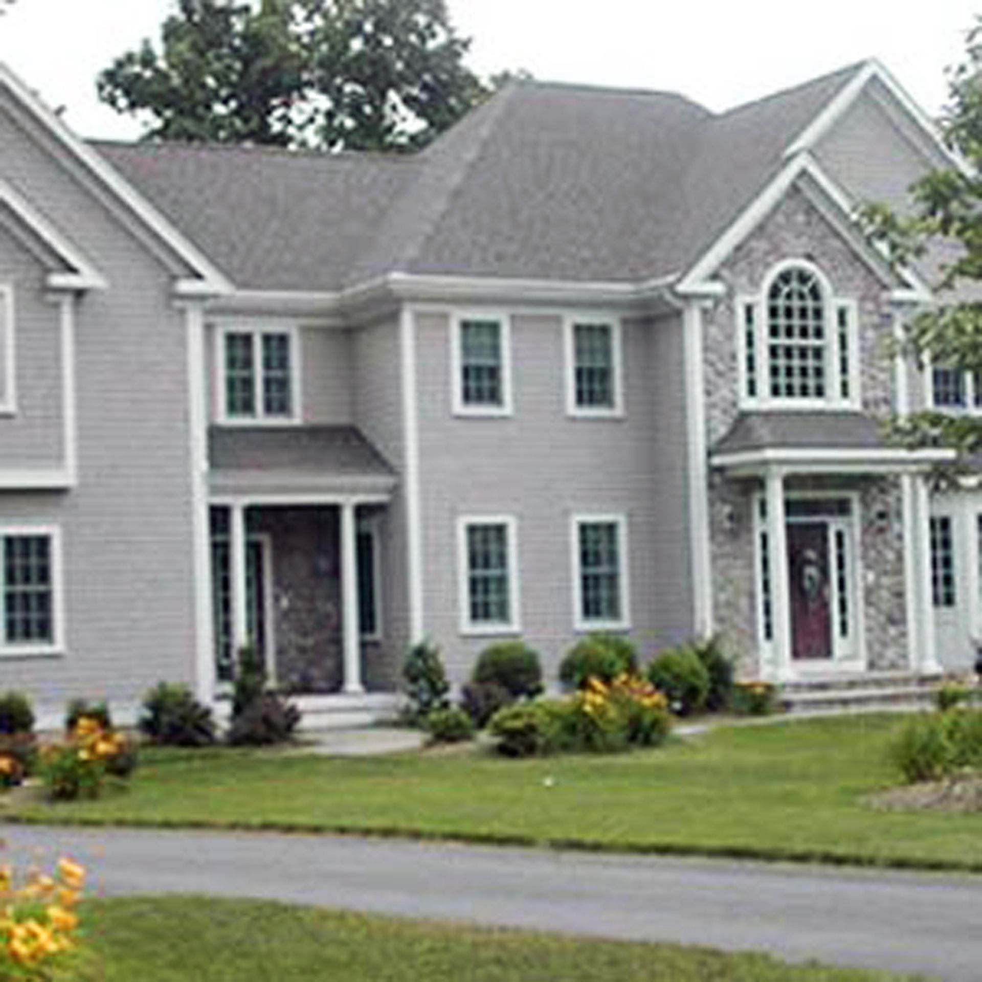 Nelson Painting is a third-generation painting business that provides exterior house painting, shown here after a colonial gray siding stone veneer project