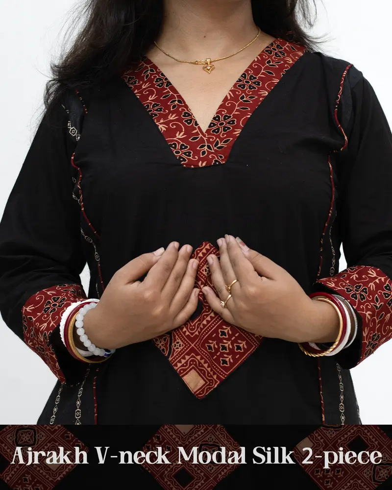 Woman wearing black Ajrakh V-neck 2-piece modal silk kurti with cuff design, side pockets, front panel Ajrakh motifs, and ethnic hand-block print detailing – SutiSaaj.