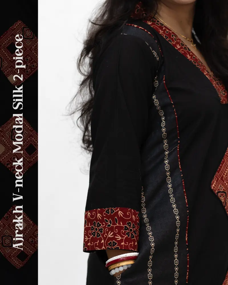 Woman wearing black Ajrakh V-neck 2-piece modal silk kurti with cuff design, side pockets, front panel Ajrakh motifs, and ethnic hand-block print detailing – SutiSaaj.