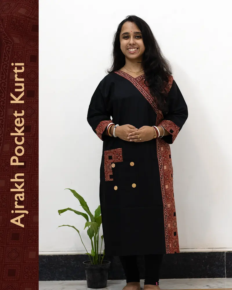 Woman wearing black pure cotton Angrakha kurti with Ajrakh block print, designed cuffs, side pocket, and decorative front buttoned pocket – SutiSaaj.
