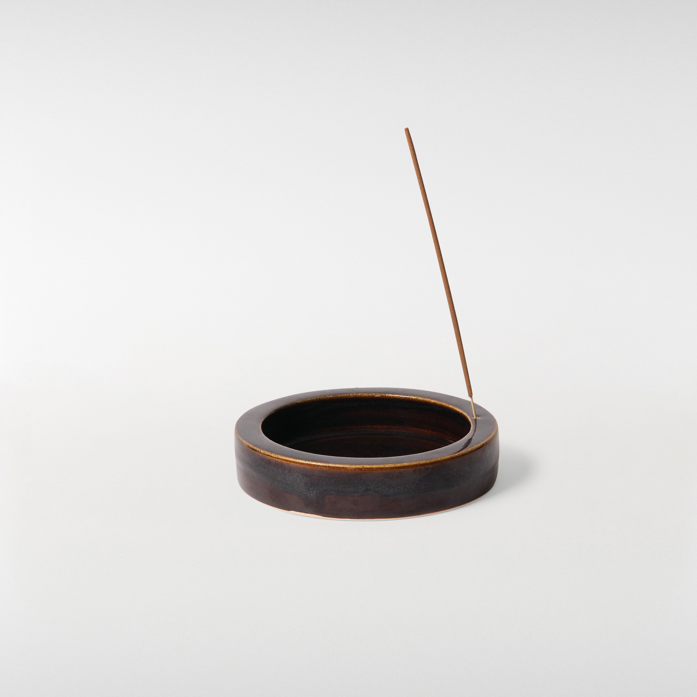 Glint Incense Holder in dark brown glaze with incense stick, minimal circular dish design