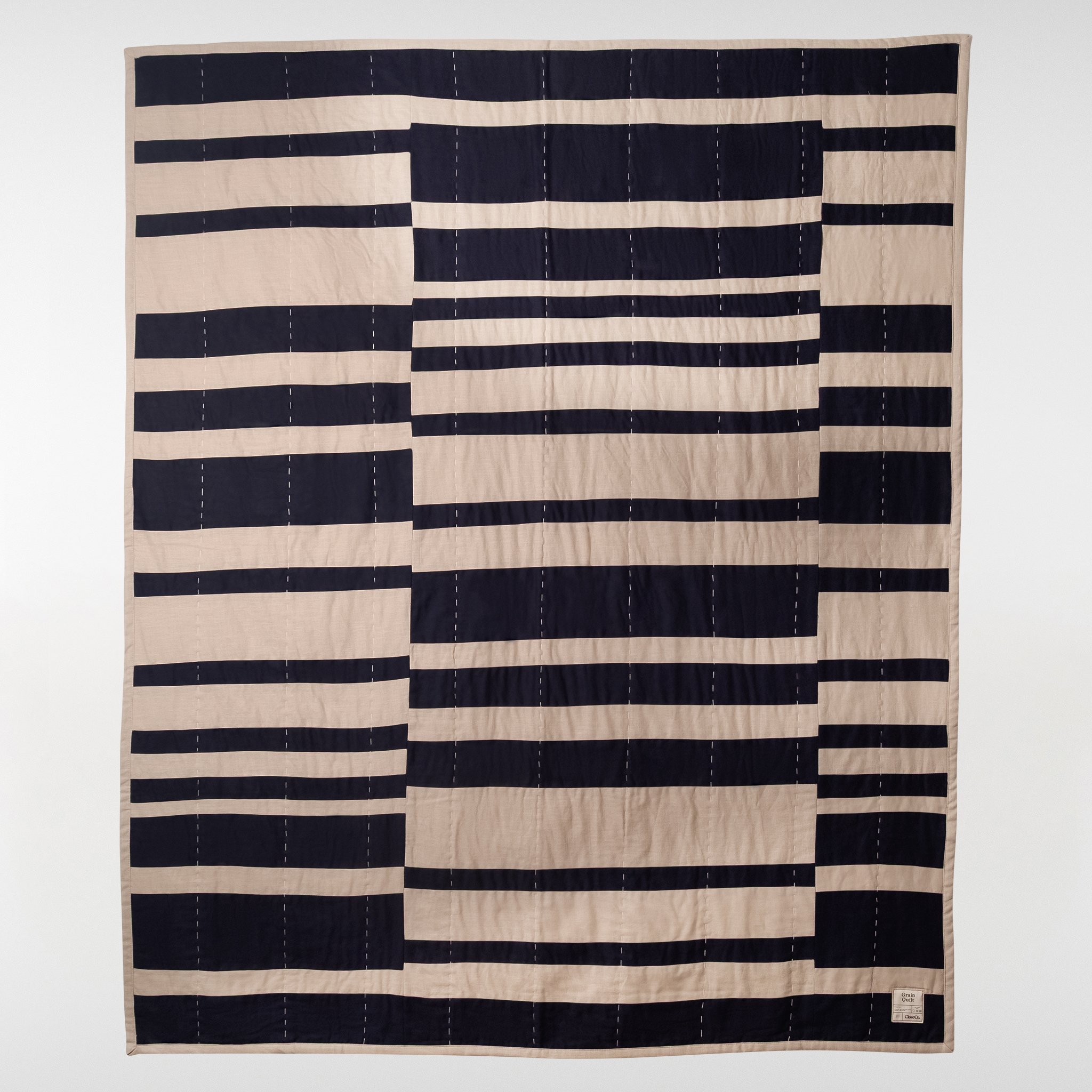Grain patchwork quilt in navy and natural tones, full view showing bold horizontal stripe pattern with stitched linen and cotton panels