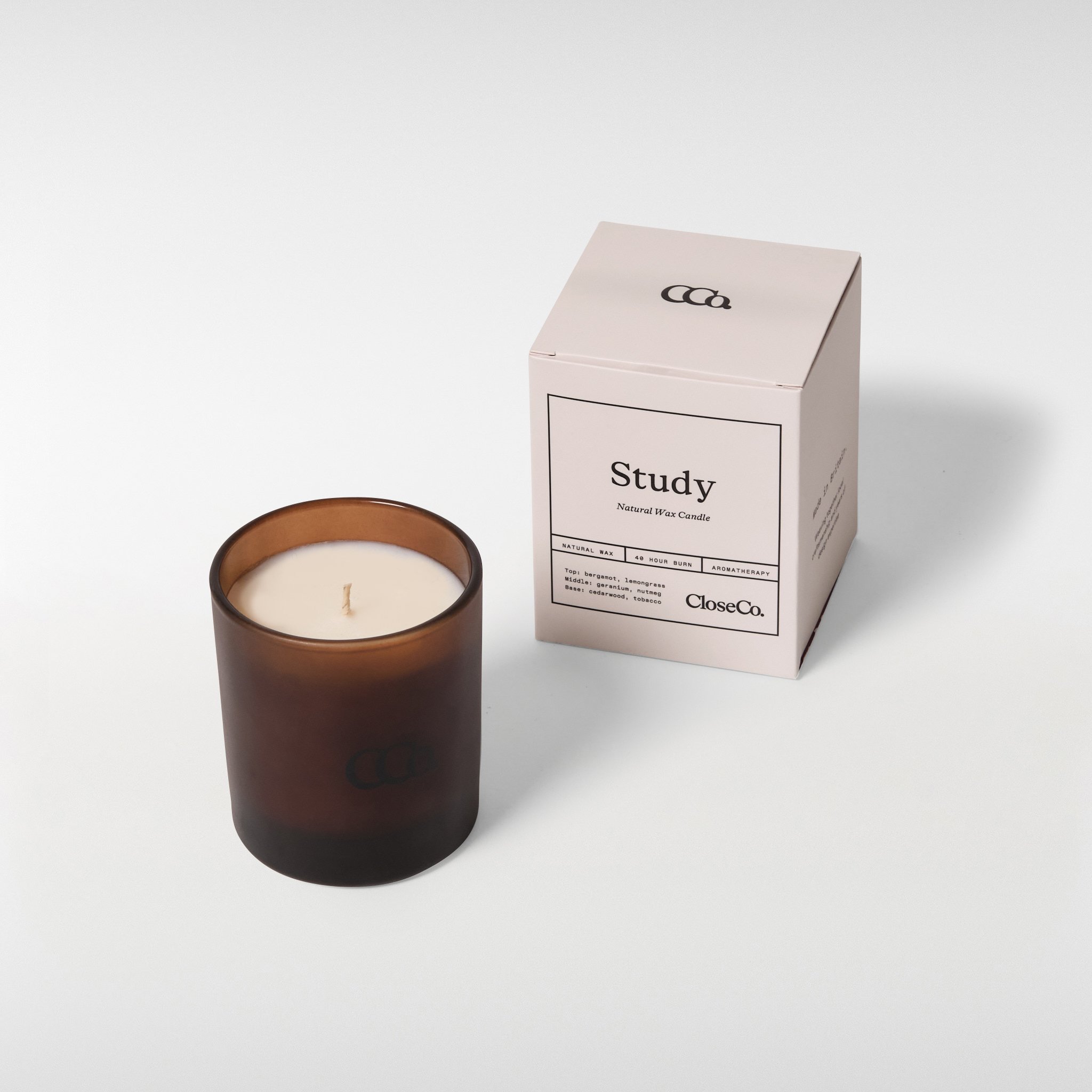 CloseCo Study candle in an amber glass vessel with a single wick, shown alongside its minimal branded box on a neutral background.