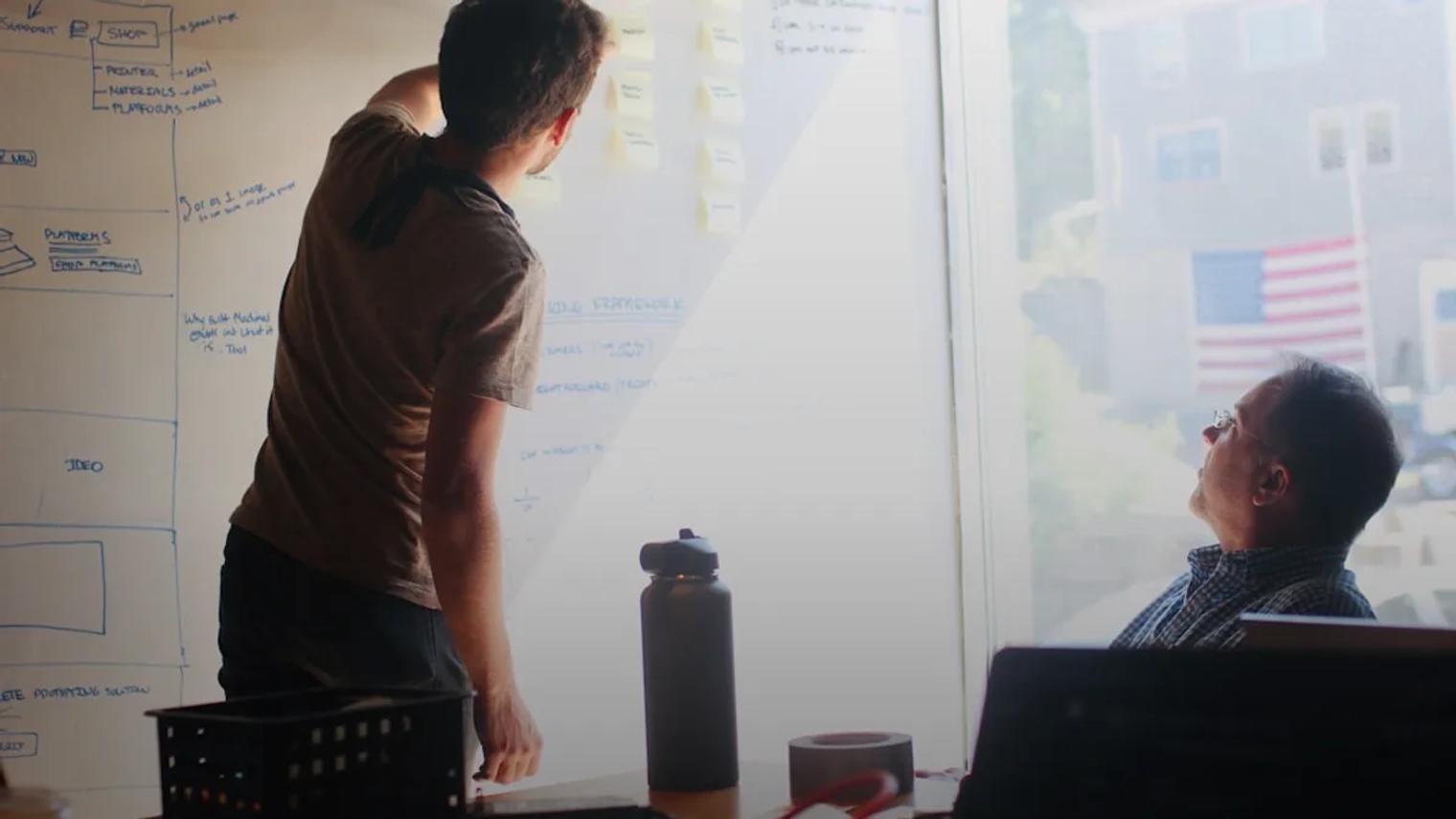 man in gray crew neck t-shirt standing near whiteboard