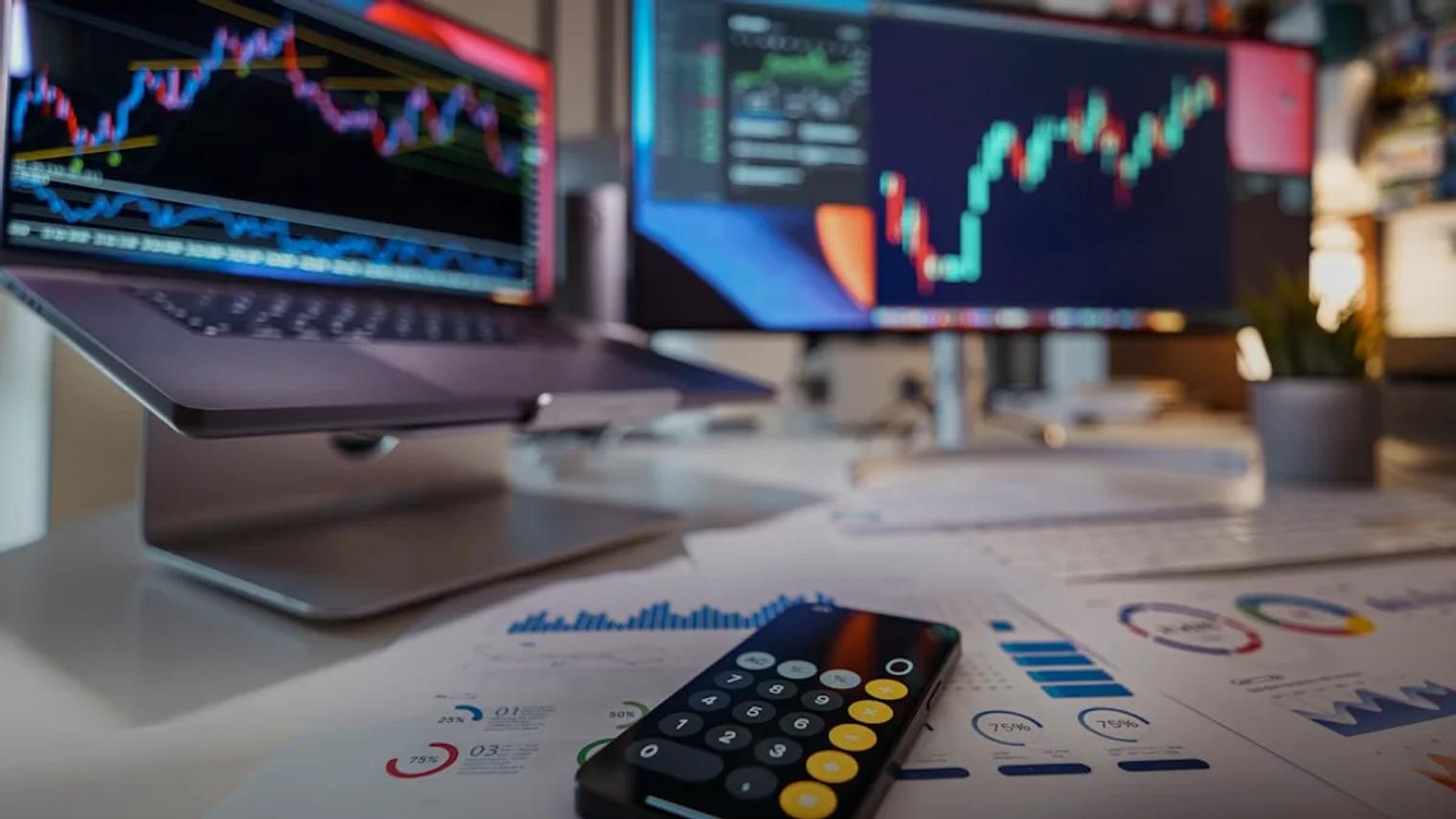 smartphone calculator on desk with financial charts behind
