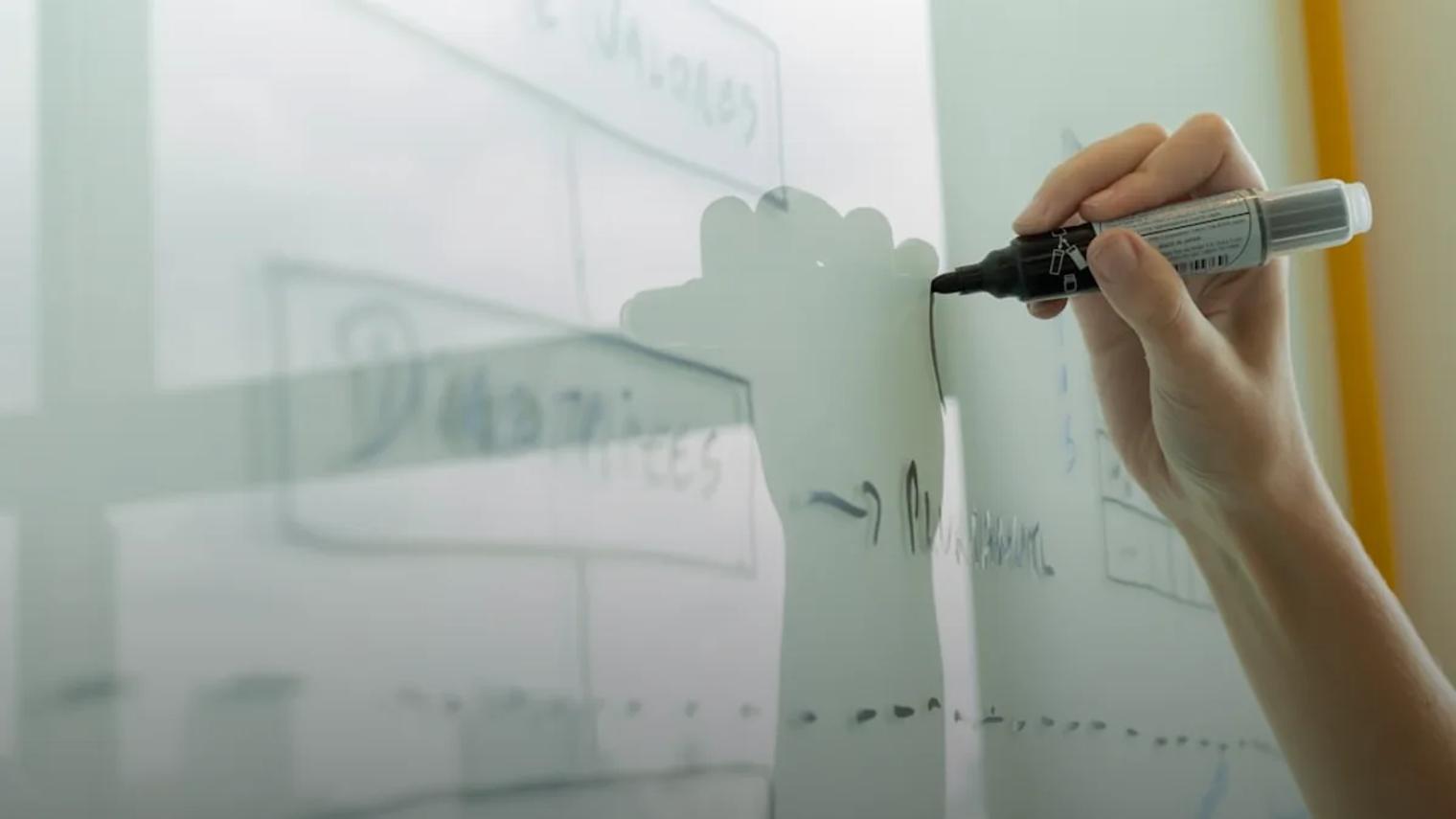 Hand drawing a diagram on a whiteboard