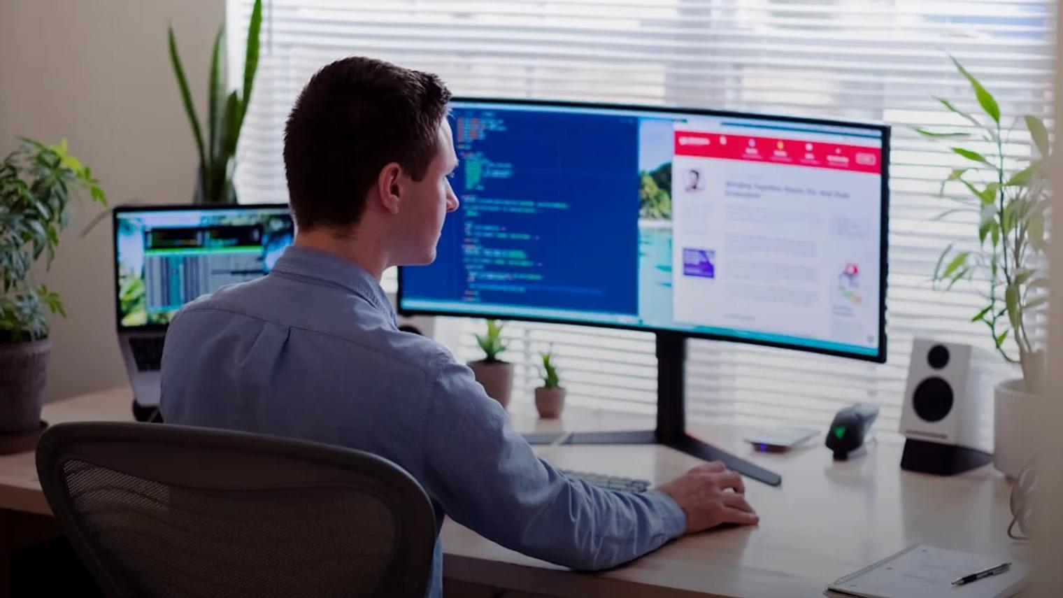 man in gray dress shirt sitting on chair in front of computer monitor