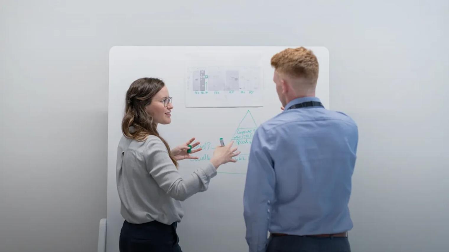 two colleagues discussing ideas at whiteboard