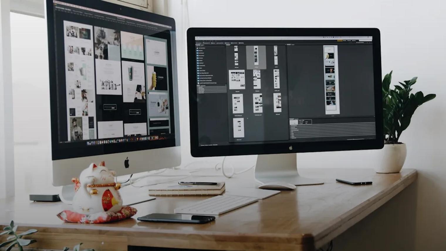 two computer monitors sitting on top of a wooden desk