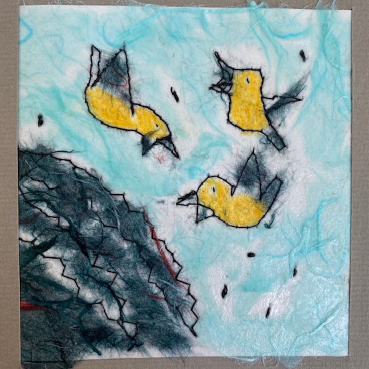 A felted panel. Three yellow birds with dark wings fly across a pale aqua sky above a dense charcoal evergreen, its branches marked by zigzag stitching. Loose fibres blur every edge.