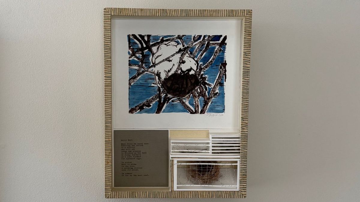 A frame edged in fine striped paper. A blue and black ink print shows a bird settled on a nest among bare branches. Below, a typed poem sits beside two small glazed compartments holding a real nest and fine threads.