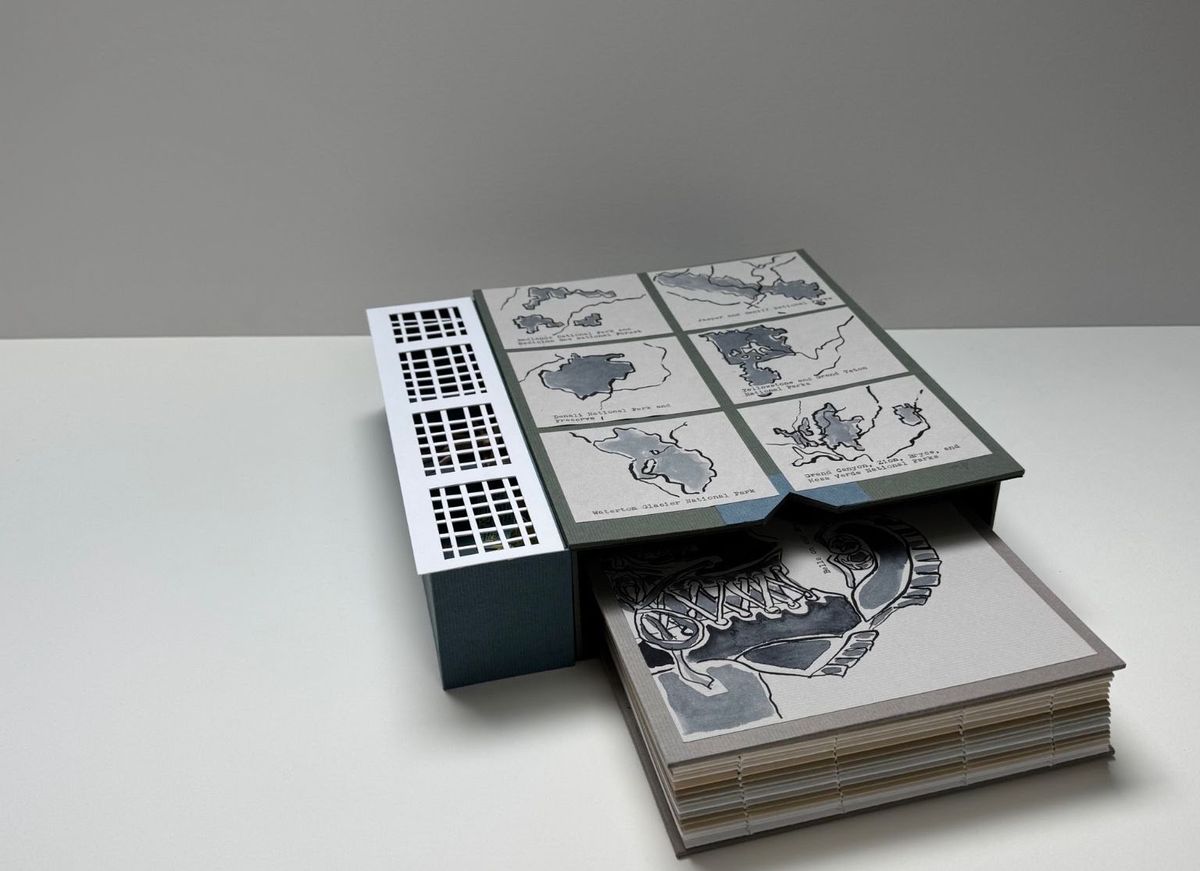 A dark green clamshell box with a pierced white lattice spine, opened to show six grey-washed lake maps with typed captions. Beneath it lies a thick book with visible spine sewing and a bold ink drawing on the cover.